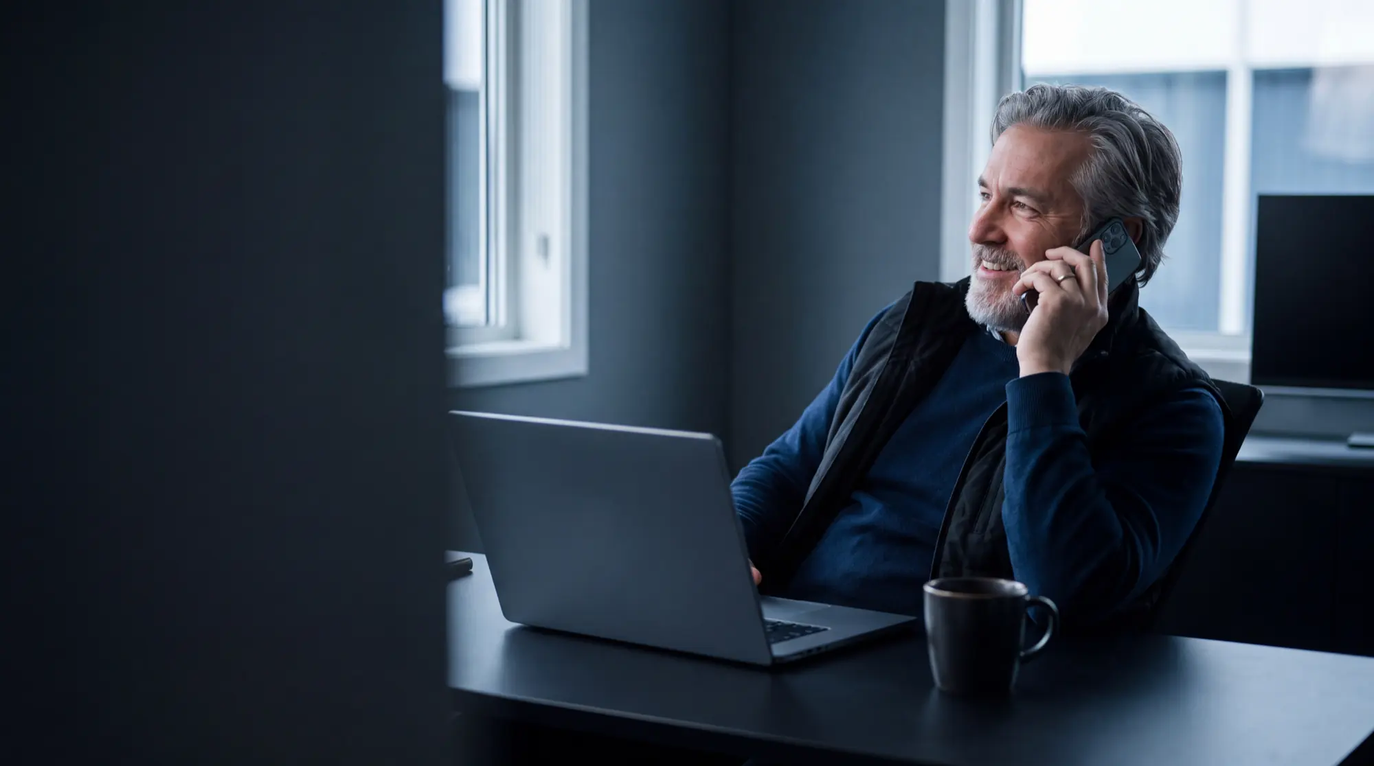 Een ondernemer belt ontspannen met zijn laptop voor zich