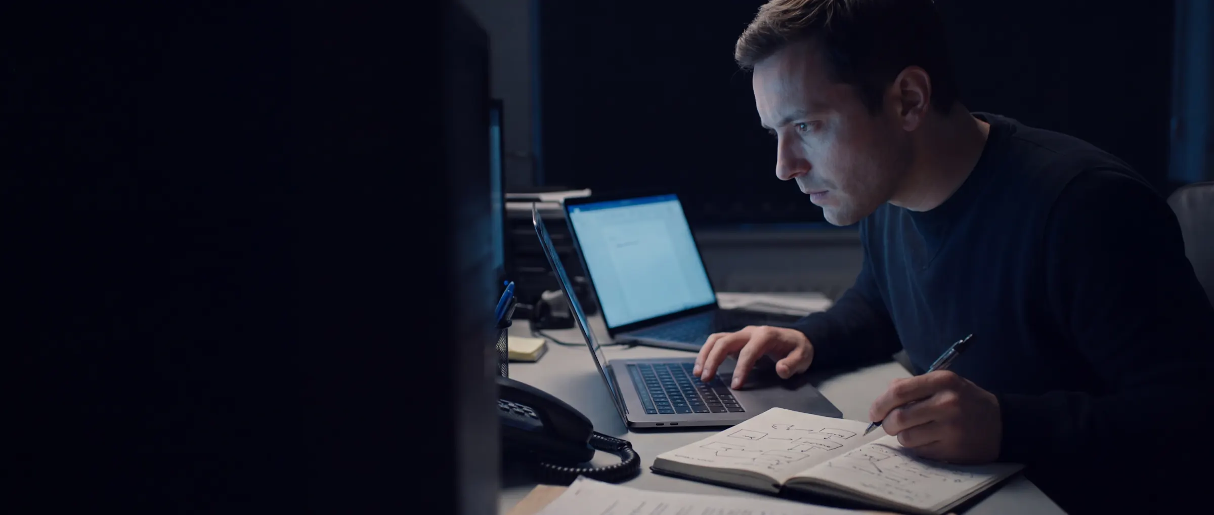 Een tester werkt geconcentreerd aan een pentest, met aantekeningen naast zijn laptop